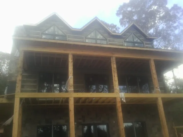 Dormers and porch framing on a large log home under construction — Roof Coating work by our crew in Ridgeland