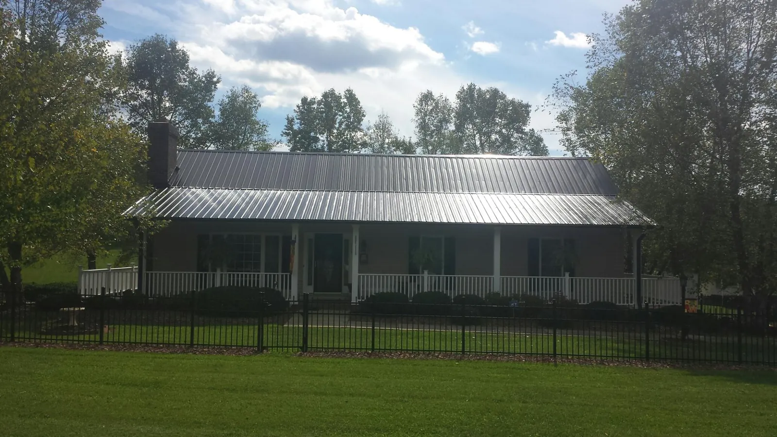 Gray metal roof on a brick ranch with a full width front porch — Gutter Guard Installation work by our crew in Ridgeland