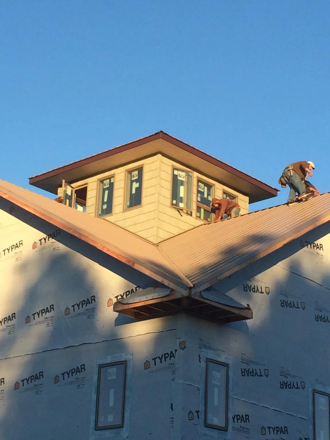 Roofers working around a rooftop cupola on a new metal roof at sunset — Roof Waterproofing in Ridgeland by Roofing Brothers